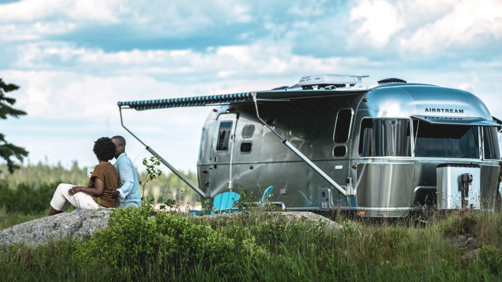 2 people chilling next to an Airstream RV